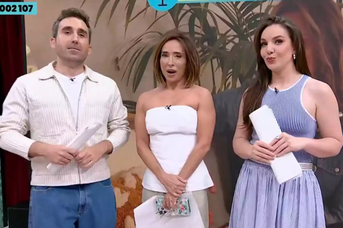 Tres presentadors de televisió, Aitor Albizua, María Patiño i Inés Hernand, posen junts en un plató decorat de La Família de la Tele amb plantes i un fons beix, cadascun sosté papers a les mans i vesteixen roba casual i elegant.