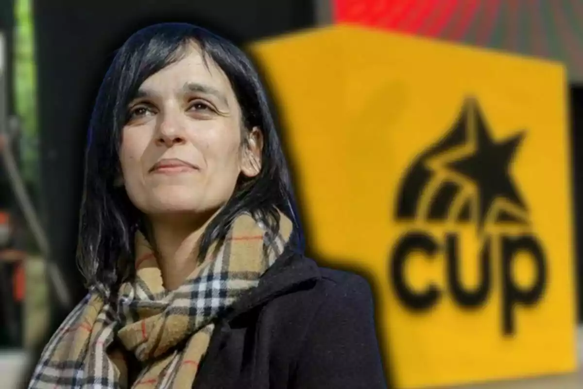 Dark-haired woman with a checkered scarf and black coat in front of a yellow sign with a blurred "cup" logo and letters.