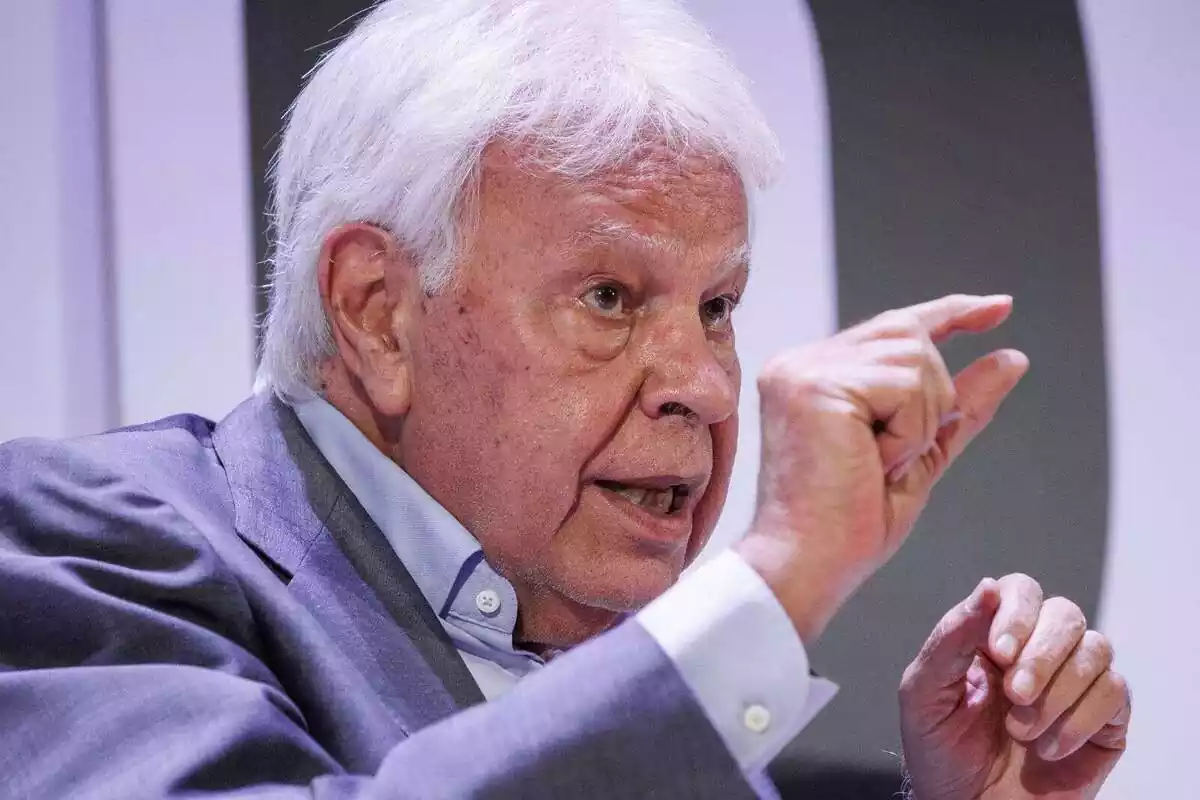 Primer pla de Felipe González parlant i fent el gest de 'petit' amb els dits índex i polze