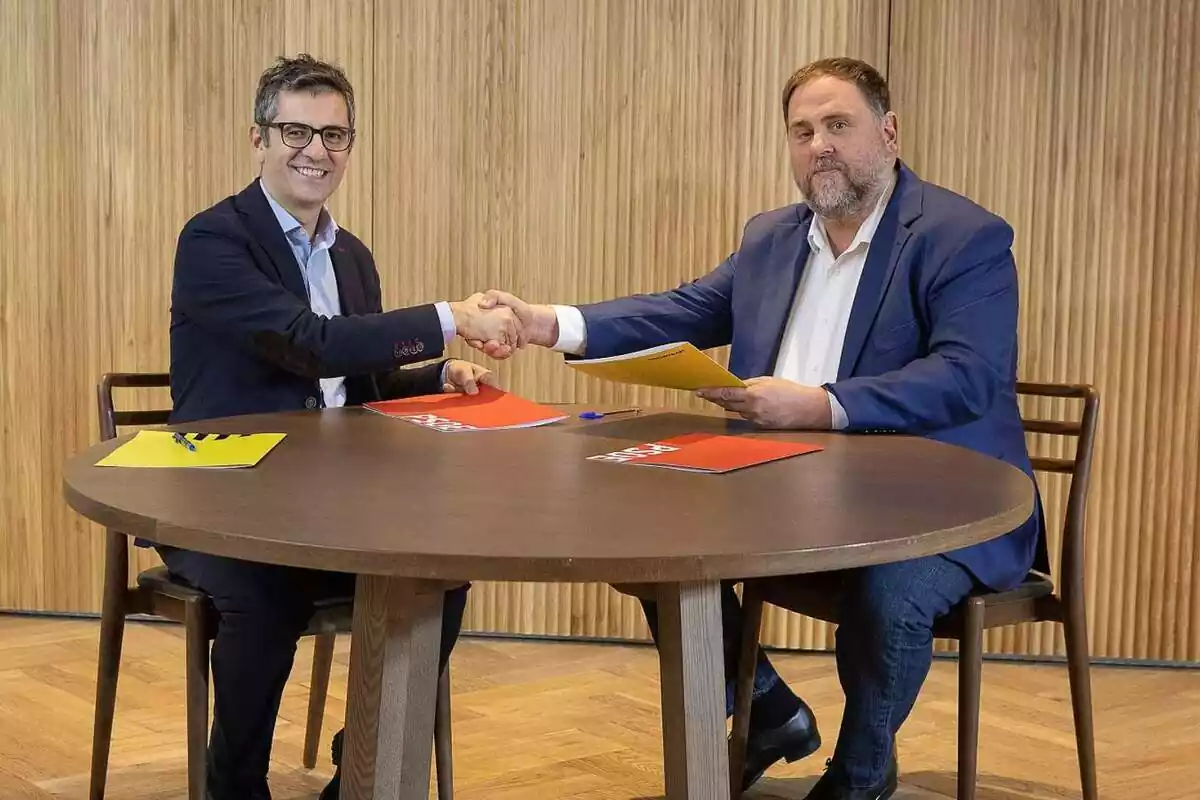 Félix Bolaños i Oriol Junqueras asseguts donant-se la mà