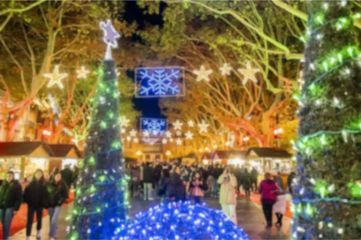 Mercat nadalenc il·luminat amb llums de colors i decoracions festives, amb persones passejant entre les parades.