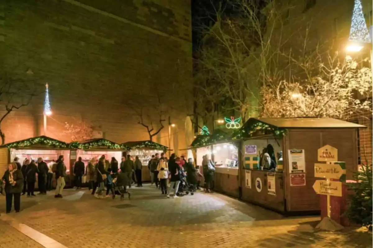 Mercat nadalenc a l'aire lliure amb casetes il·luminades i persones passejant a la nit.