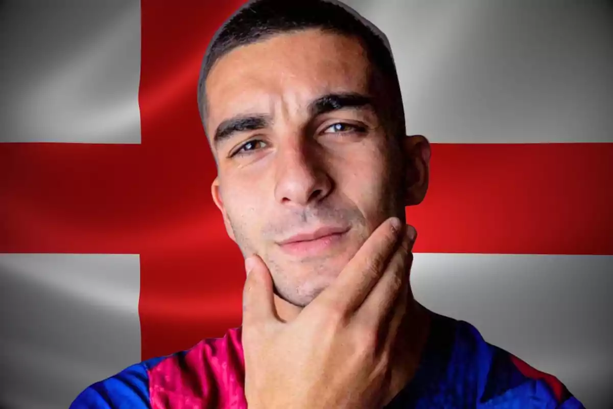 Young man in a blue and red sports jersey posing thoughtfully in front of a flag with a red cross on a white background