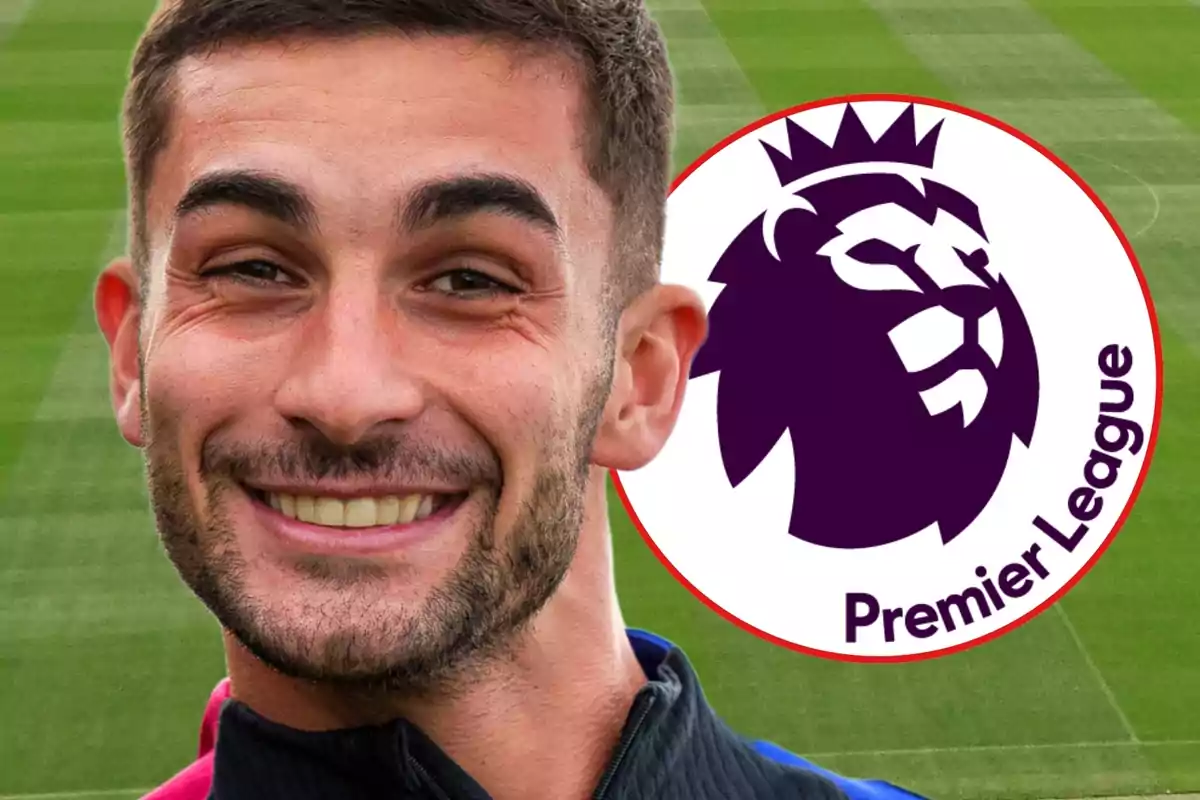 Un hombre sonriente frente a un campo de fútbol con el logo de la Premier League al lado.