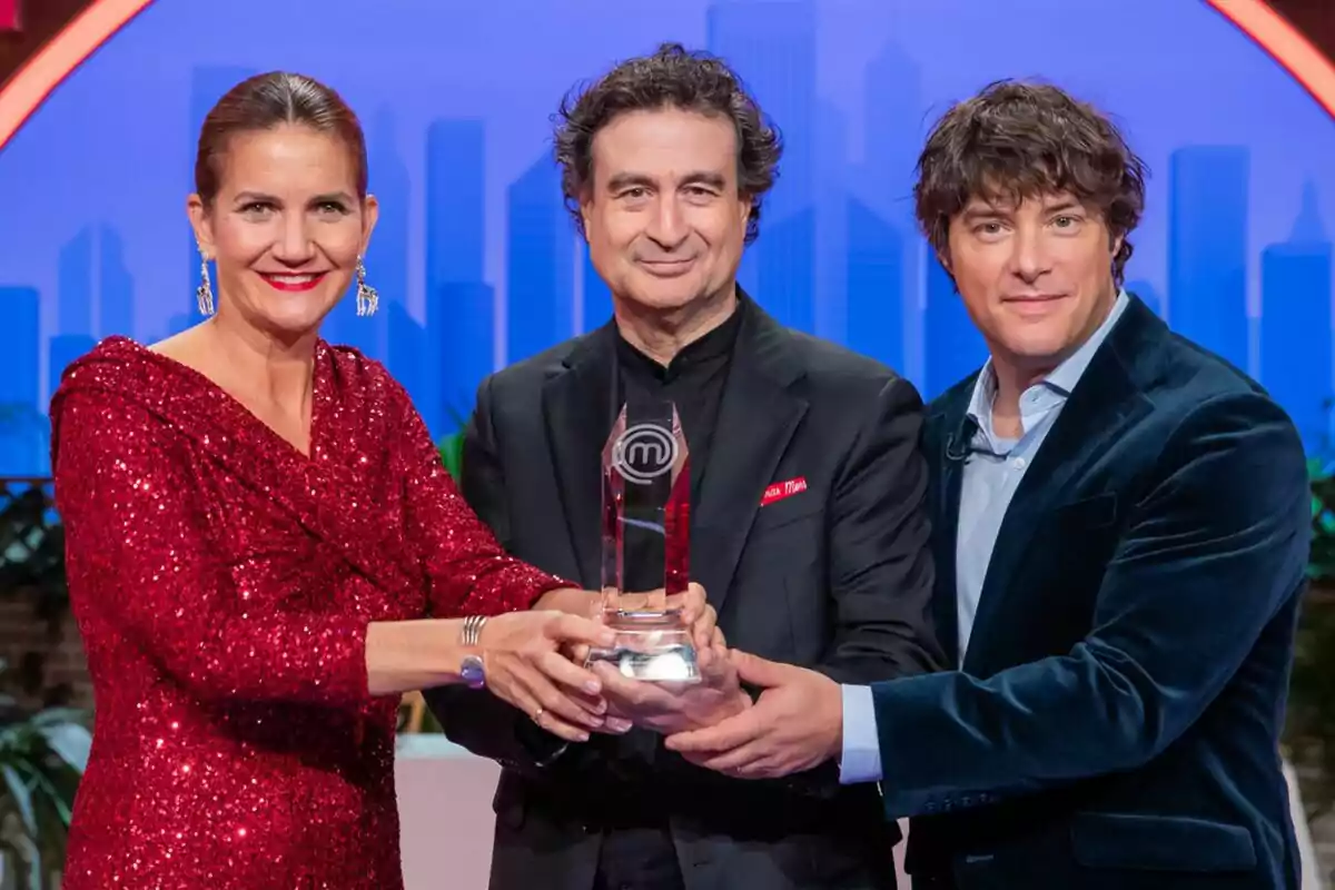 Pepe Rodríguez, Jordi Cruz y Samantha Vallejo-Nágera sostienen un trofeo de MasterChef Junior en un escenario con fondo azul.