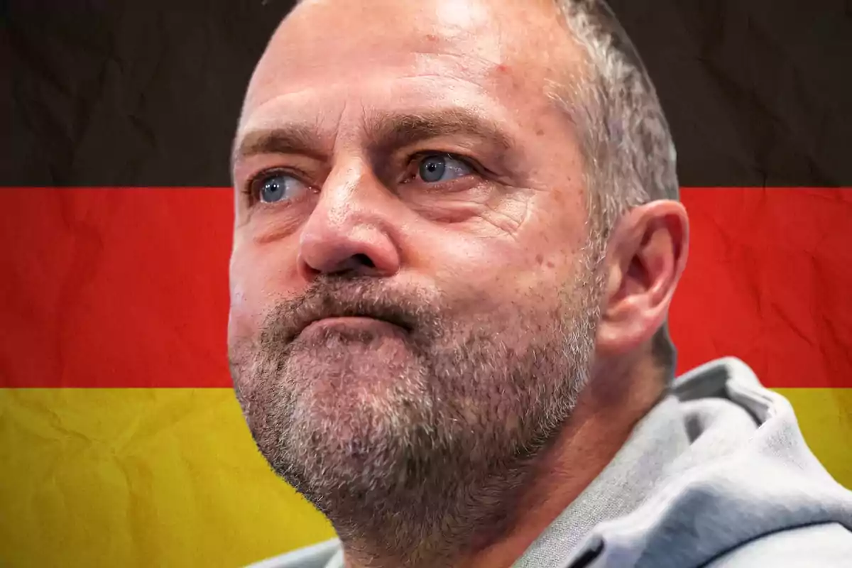 Home d’expressió seriosa amb barba i cabell curt davant d’una bandera d’Alemanya desenfocada