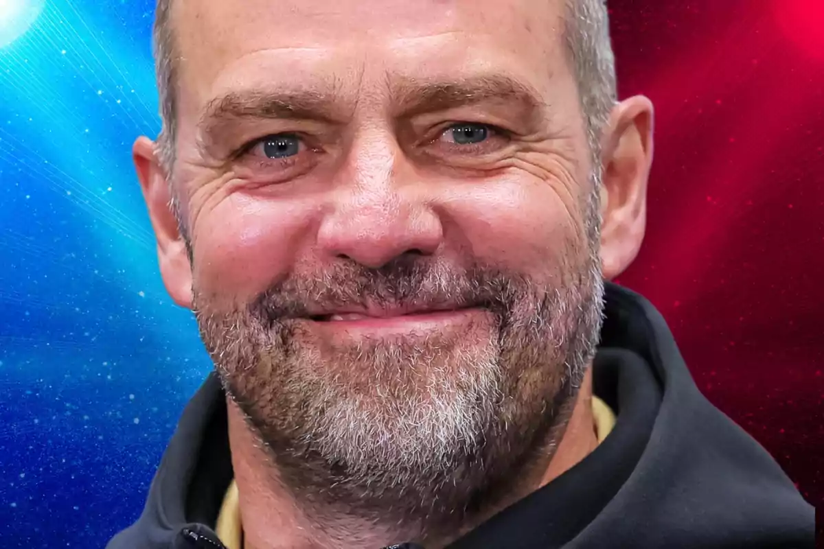 Un hombre sonriente con barba y fondo de colores azul y rojo.