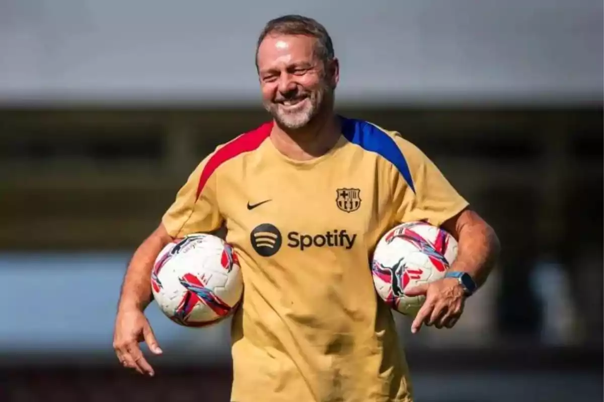 Un home somrient amb una samarreta d´entrenament del FC Barcelona, sostenint dues pilotes de futbol. Un home somrient amb una samarreta d´entrenament del FC Barcelona, sostenint dues pilotes de futbol.