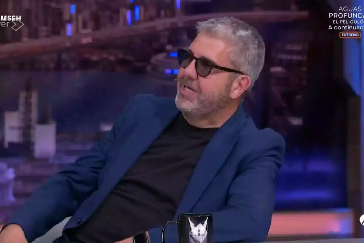Florentino Fernández amb ulleres de sol i barba està assegut a El Hormiguero, vestint una jaqueta blava i samarreta negra, mentre somriu i sembla estar conversant. Florentino Fernández amb ulleres de sol i barba està assegut a El Hormiguero, vestint una jaqueta blava i samarreta negra, mentre somriu i sembla estar conversant.