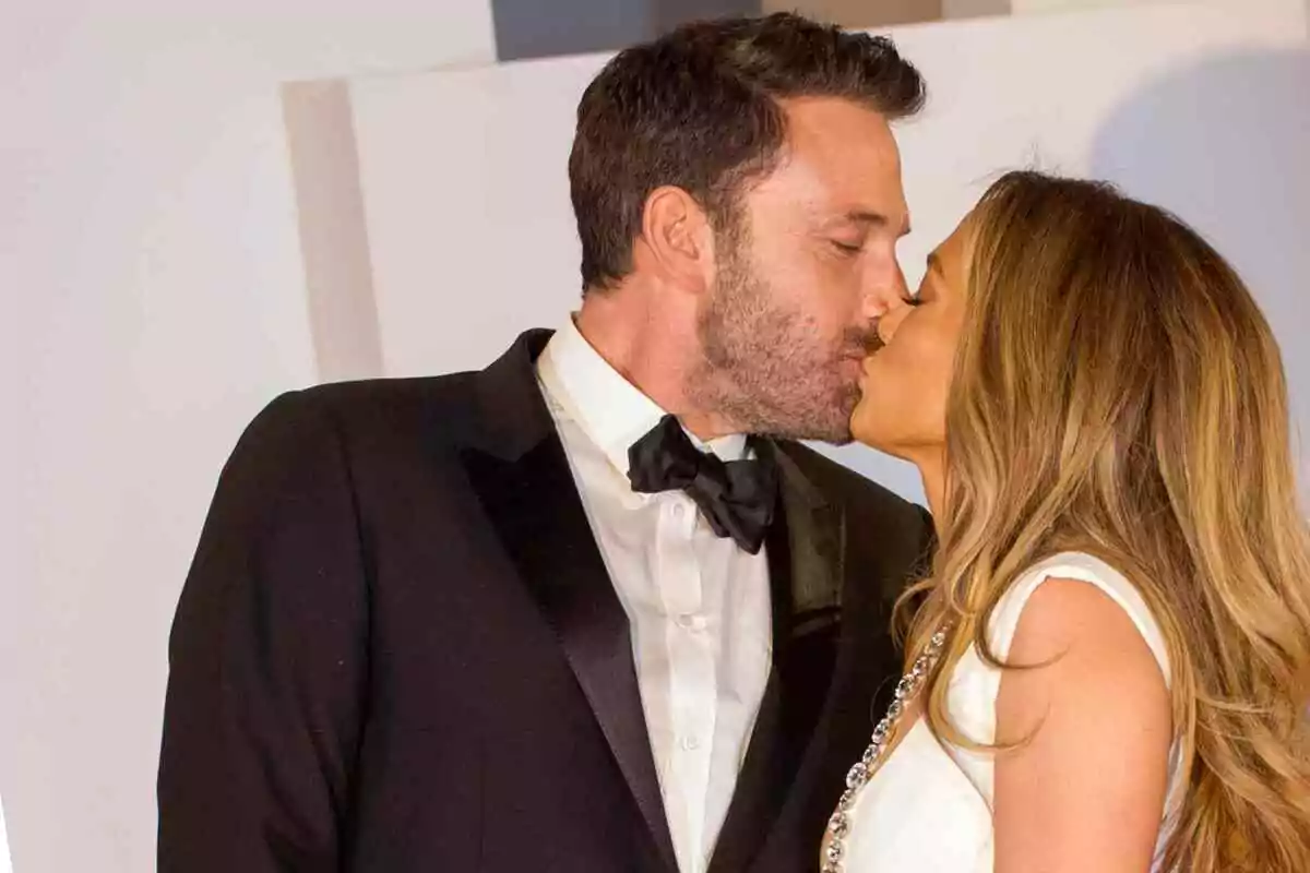 Jennifer López and Ben Affleck elegantly dressed people sharing a kiss.