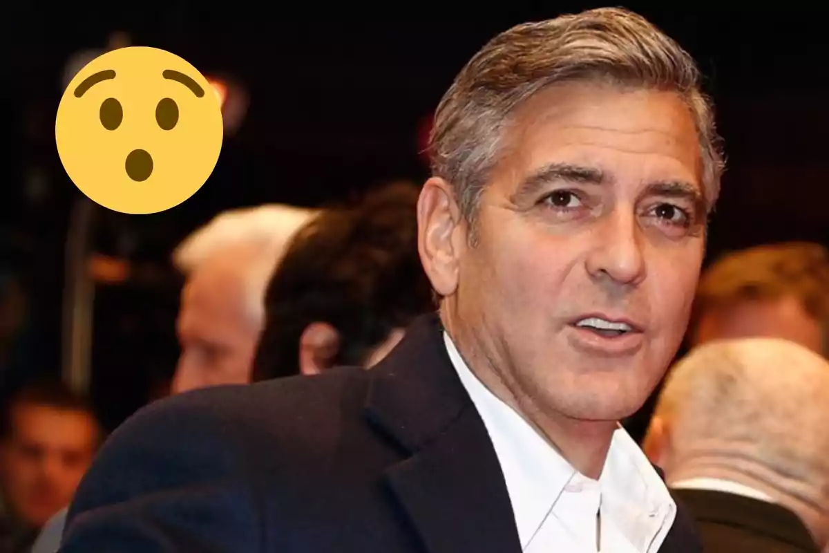 George Clooney at an event with a surprised emoji next to him.