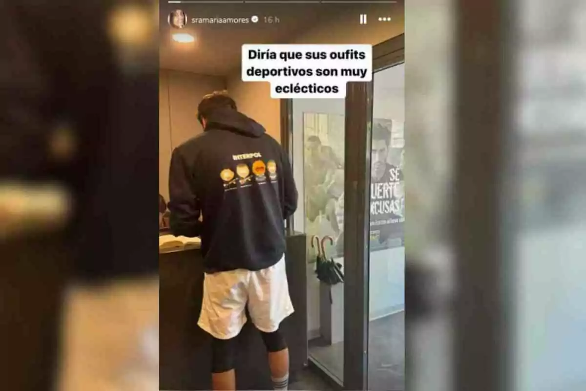 Ion Aramendi d'esquena amb una dessuadora negra i pantalons curts blancs està en un interior, amb un cartell a la paret i un text superposat que diu Ion Aramendi d'esquena amb una dessuadora negra i pantalons curts blancs està en un interior, amb un cartell a la paret i un text superposat que diu