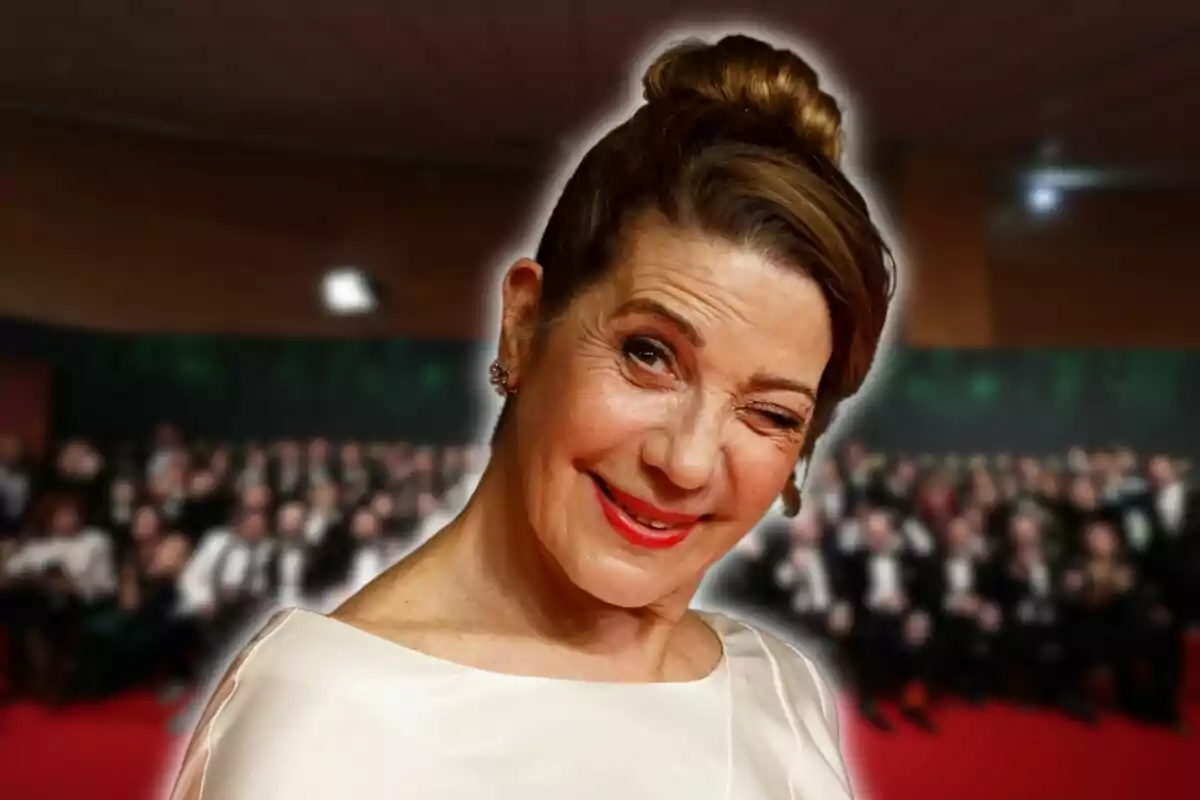 A smiling woman winking at an event with a background of blurred people.