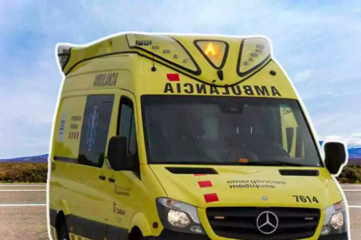 Una ambulància groga amb la paraula "AMBULANCIA" escrita a la part frontal i lateral, estacionada en una carretera amb un cel blau de fons.