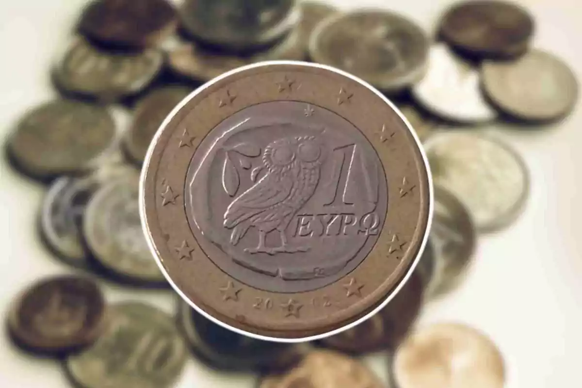 1 euro coin with an owl in the middle and several coins out of focus in the background.