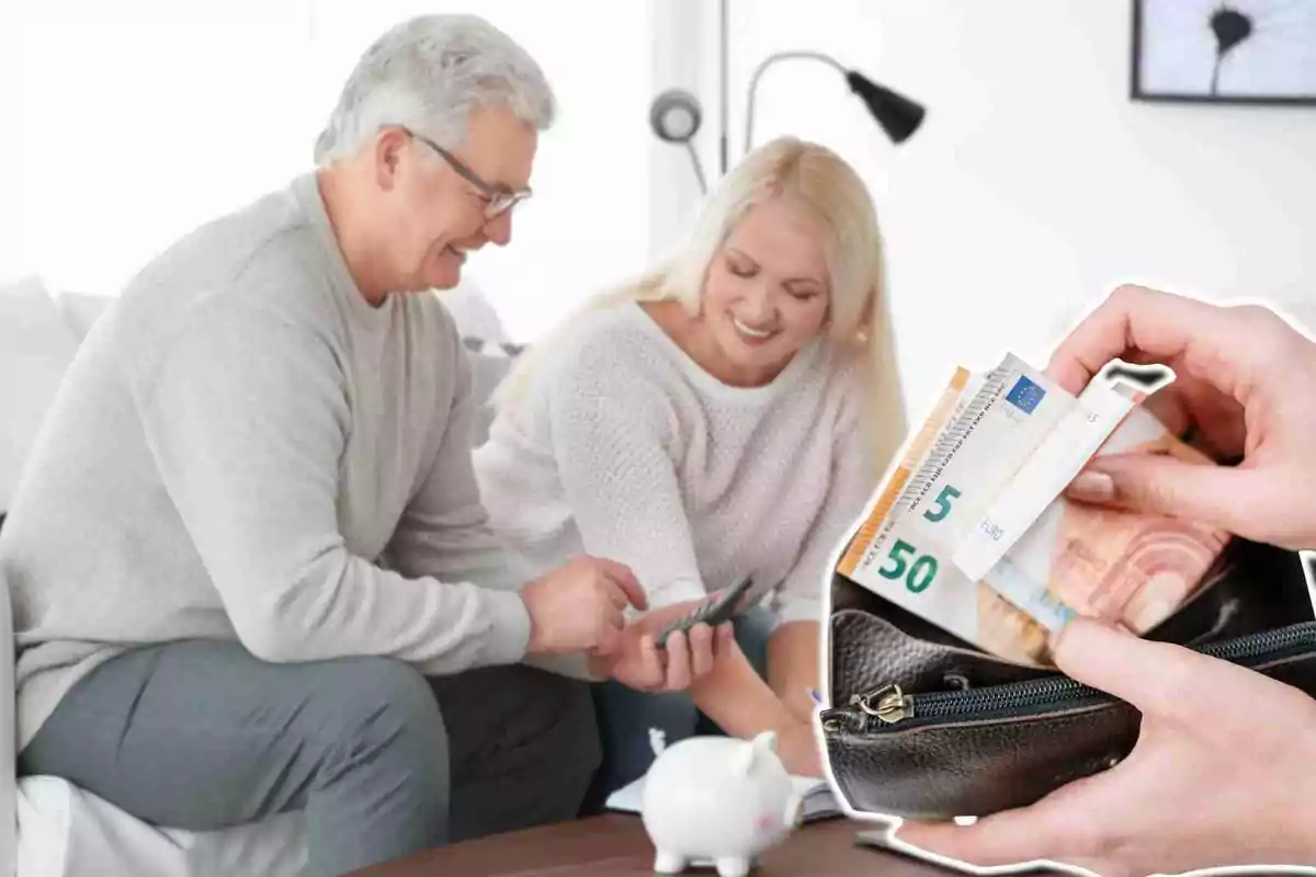 Una parella gran somrient revisa les seves finances a casa mentre una mà treu bitllets d'euro d'una cartera.