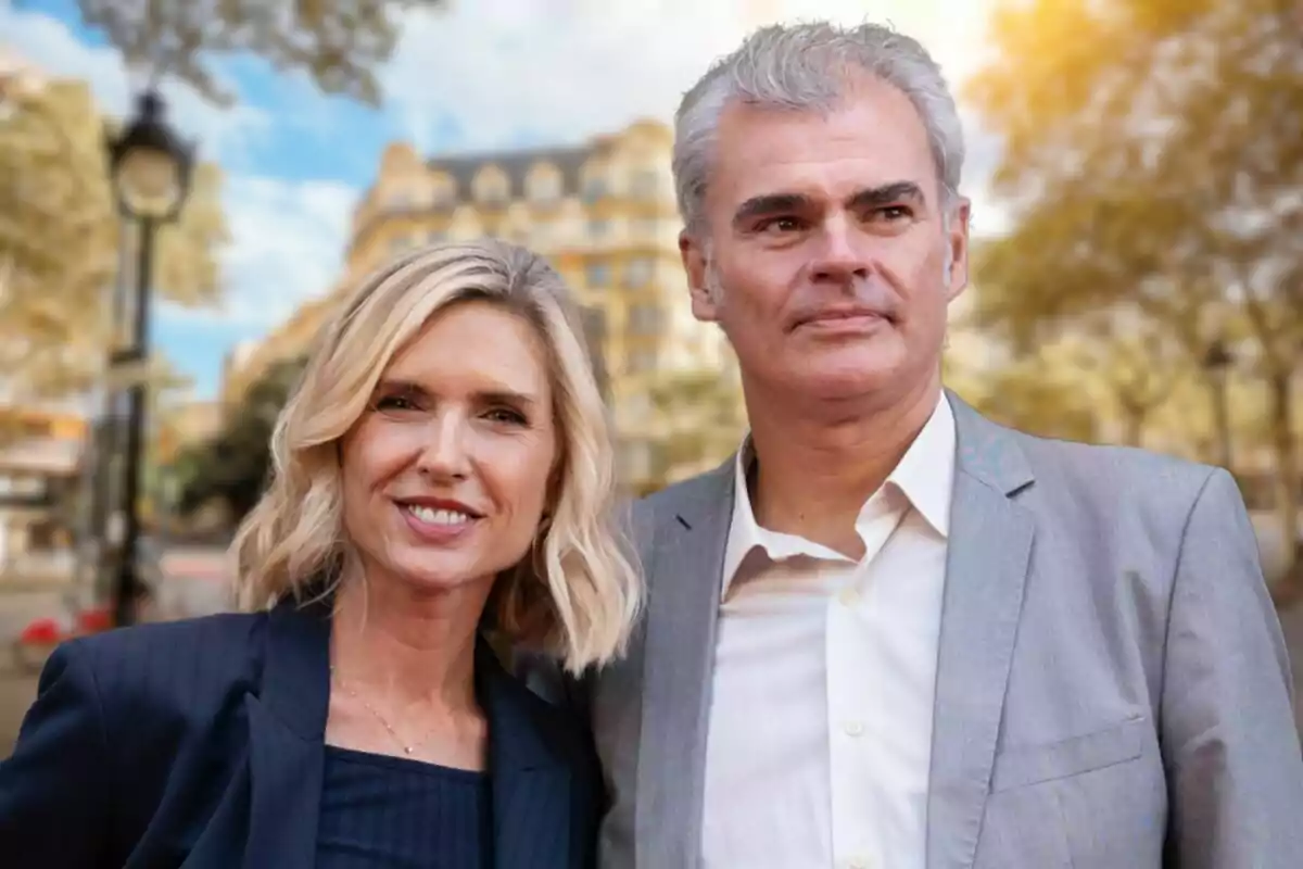 A smiling couple poses outdoors with a blurry building and trees in the background.