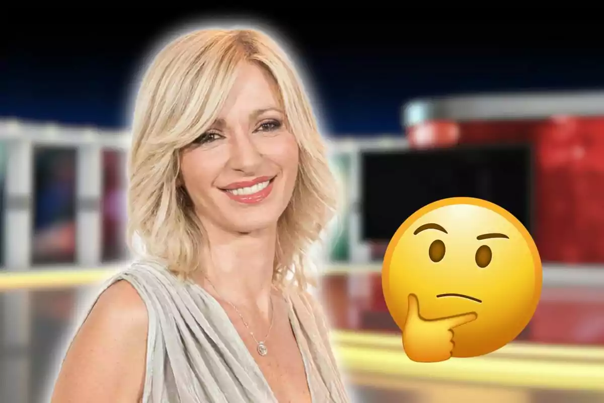 Una mujer rubia sonriente con un emoji pensativo superpuesto en un fondo de estudio de televisión.