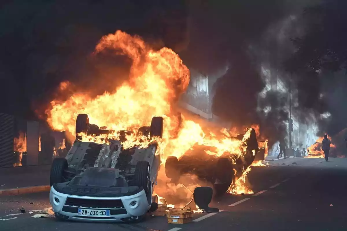 Imatge dels disturbis a França, amb dos cotxes bolcats en flames Imatge dels disturbis a França, amb dos cotxes bolcats en flames
