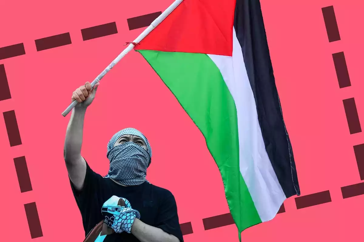 Un home amb la cara tapada subjectant una bandera de palestina