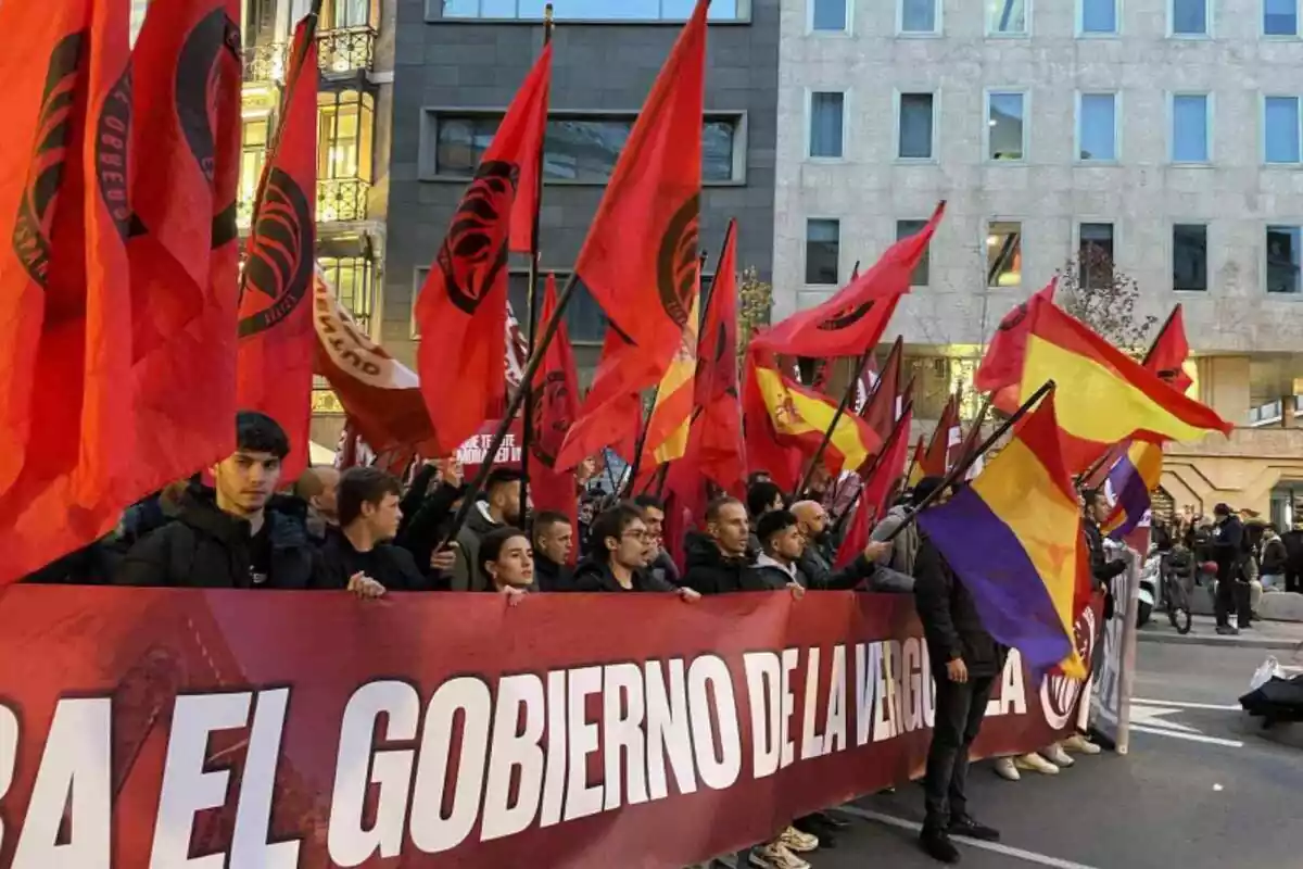 Desenes de militants del Frente Obrero darrere una pancarta vermella i portant banderes vermelles amb el logo del Frente Obrero