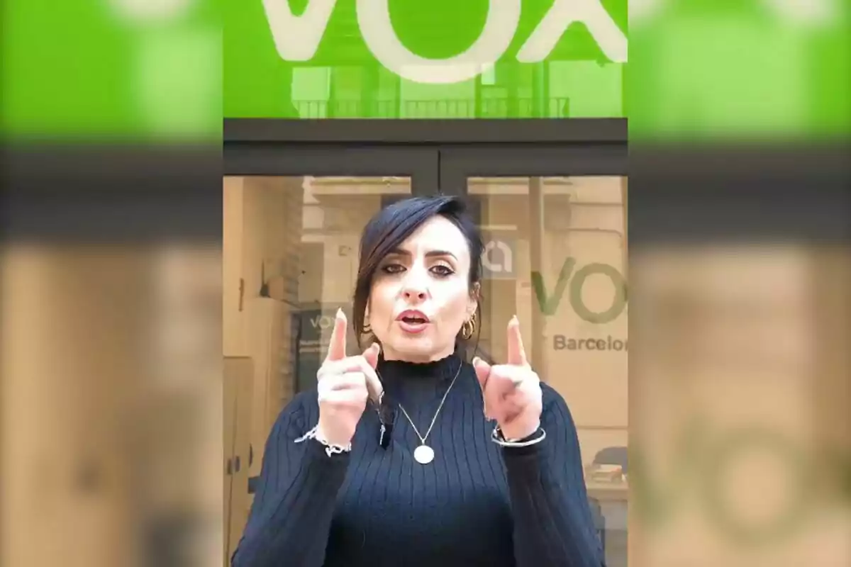 A person speaking in front of an office with a green sign in the background.