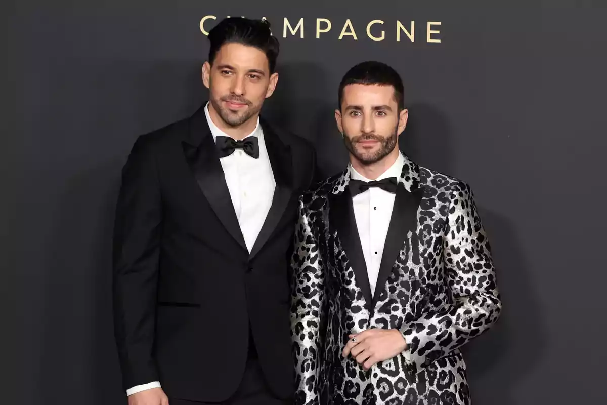 Gal Marom and Pelayo Díaz pose at a formal event, one wearing a classic black tuxedo and the other a leopard print tuxedo. Gal Marom and Pelayo Díaz pose at a formal event, one wearing a classic black tuxedo and the other a leopard print tuxedo.