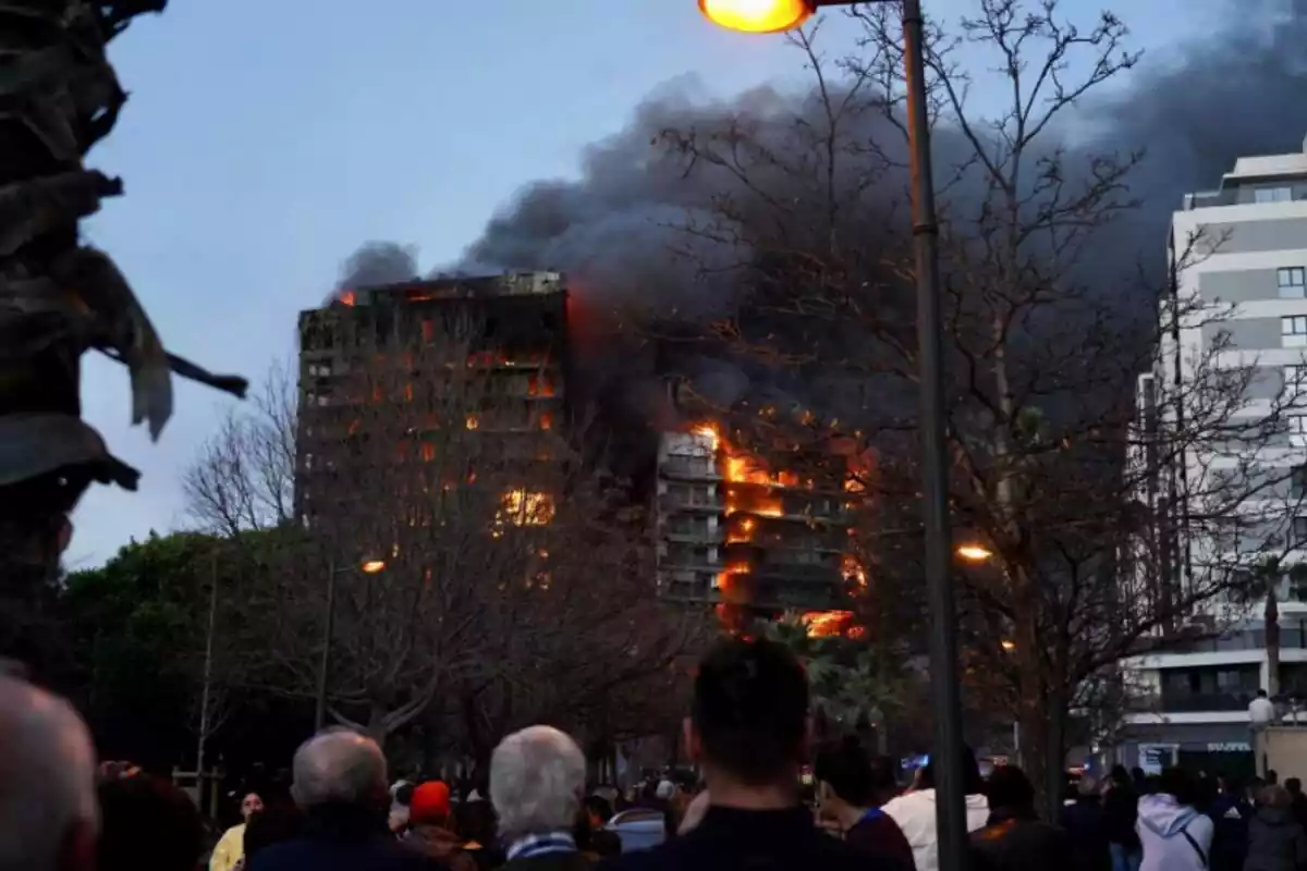 Gent presenciant l'incendi de l'edifici de València amb flames sortint pels balcons