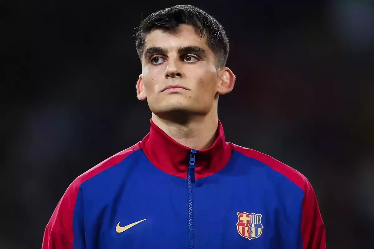 Un jugador de futbol amb jaqueta blava i vermella del FC Barcelona a un estadi.