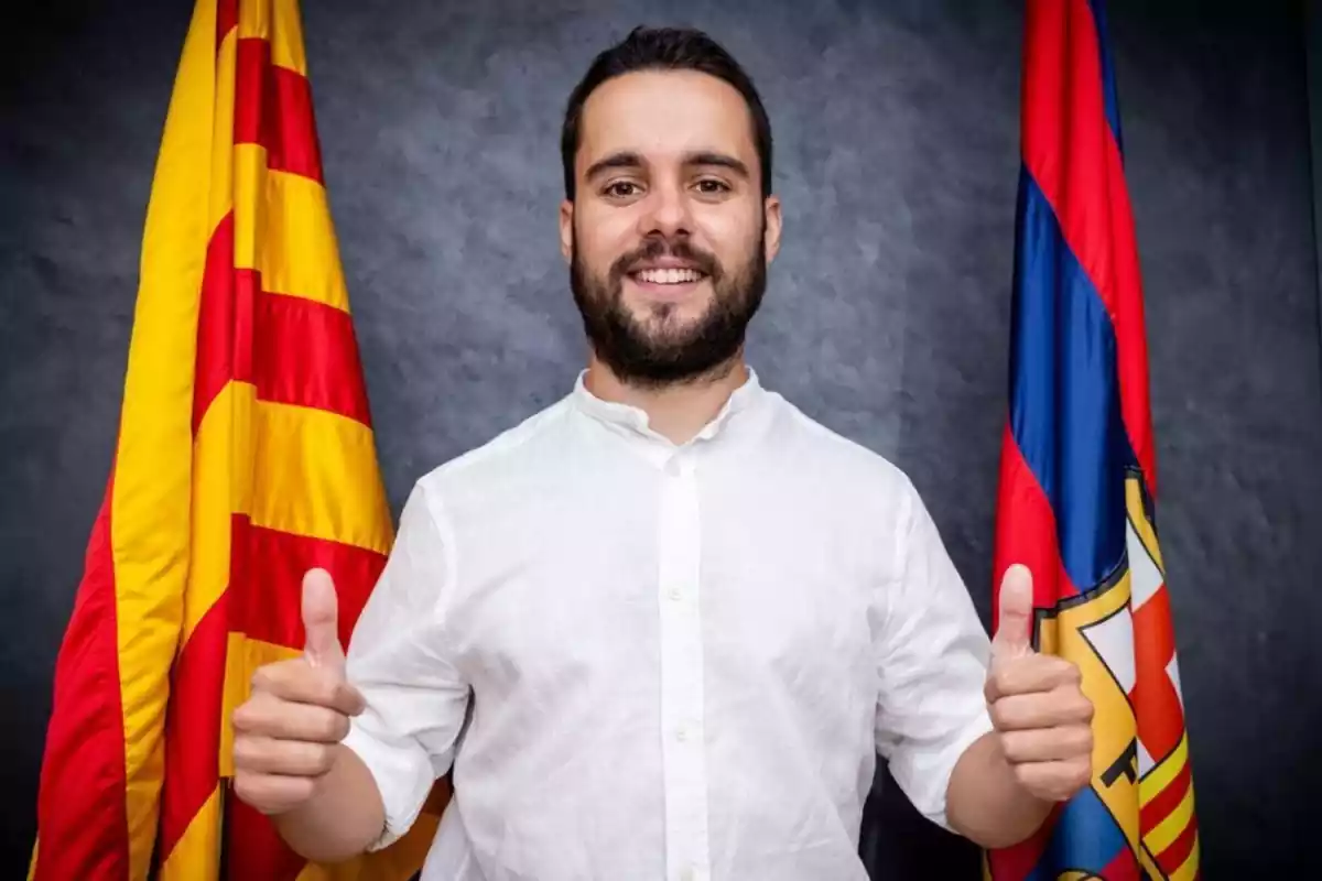 Jonatan Giráldez posa amb els polzes cap amunt davant una bandera del FC Barcelona