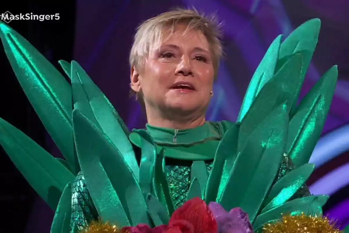 Gloria Serra amb una disfressa de pinya brillant amb detalls en forma de fulles en un escenari de Mask Singer.