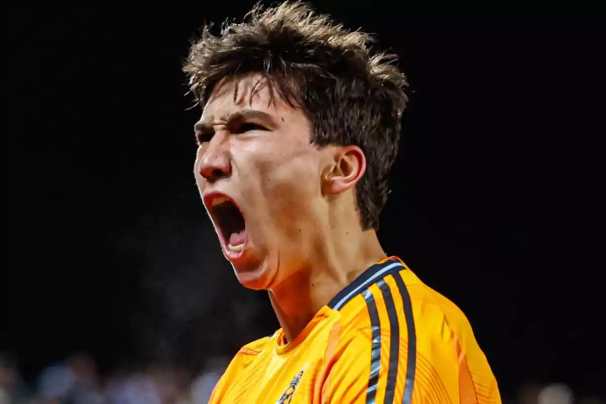 Young man in an orange sports uniform shouts with an expression of euphoria during a nighttime event