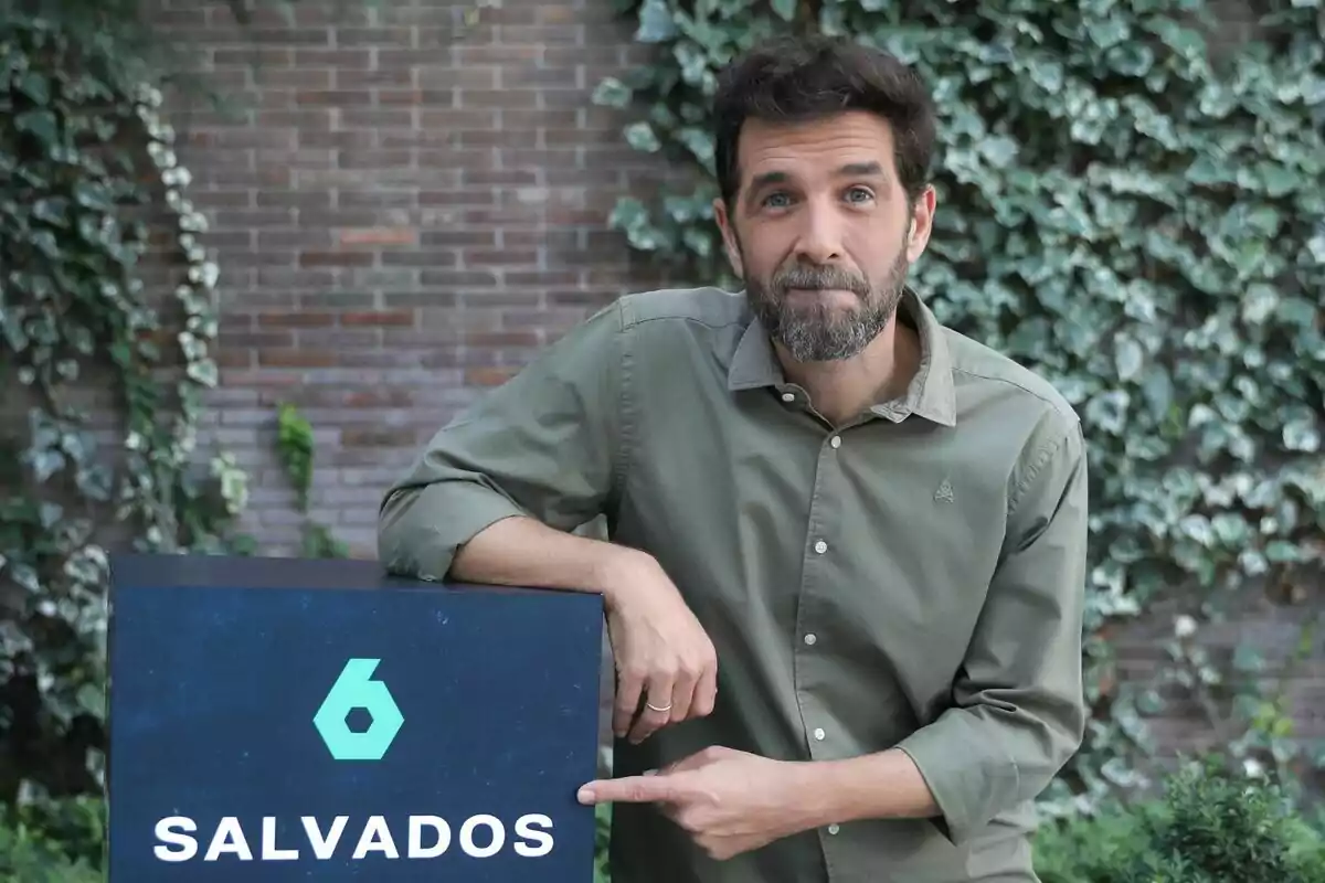 Gonzo amb barba i camisa verda assenyala un cartell que diu "Salvados" amb un logotip de laSexta