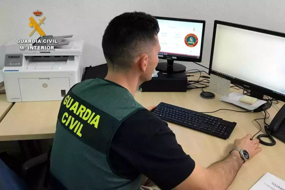 Guàrdia Civil amb un ordinador amb dues pantalles i una impressora al costat