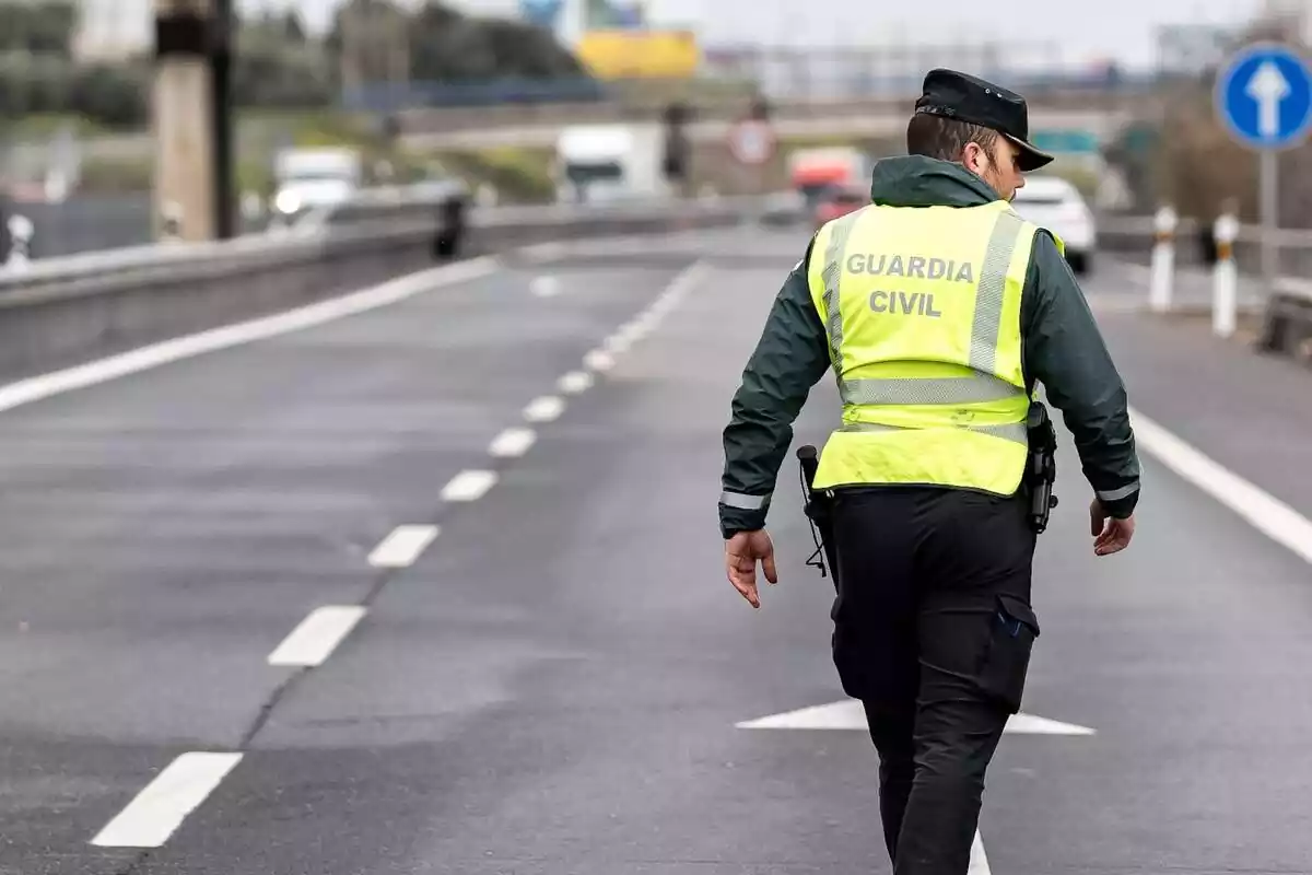 Plànol mitjà d'un guàrdia civil d'esquena al mig d'una carretera