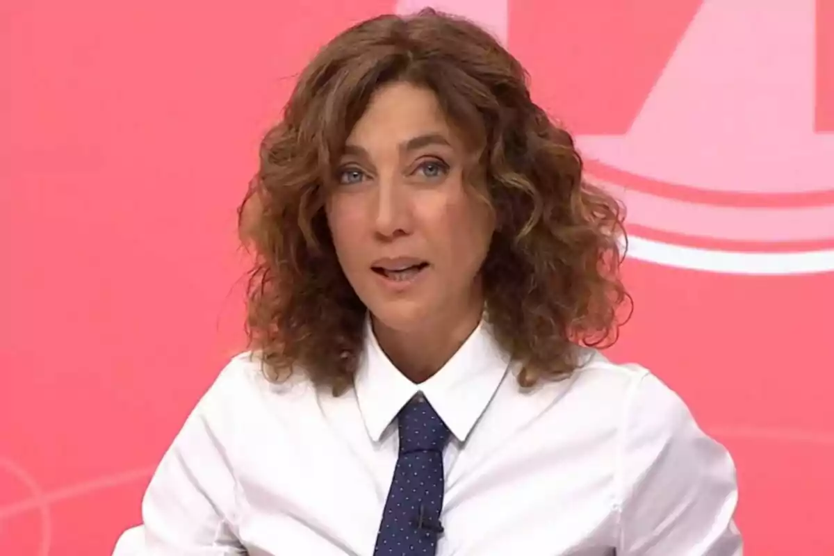 Mujer con cabello rizado y camisa blanca con corbata azul sobre fondo rosa. Mujer con cabello rizado y camisa blanca con corbata azul sobre fondo rosa.
