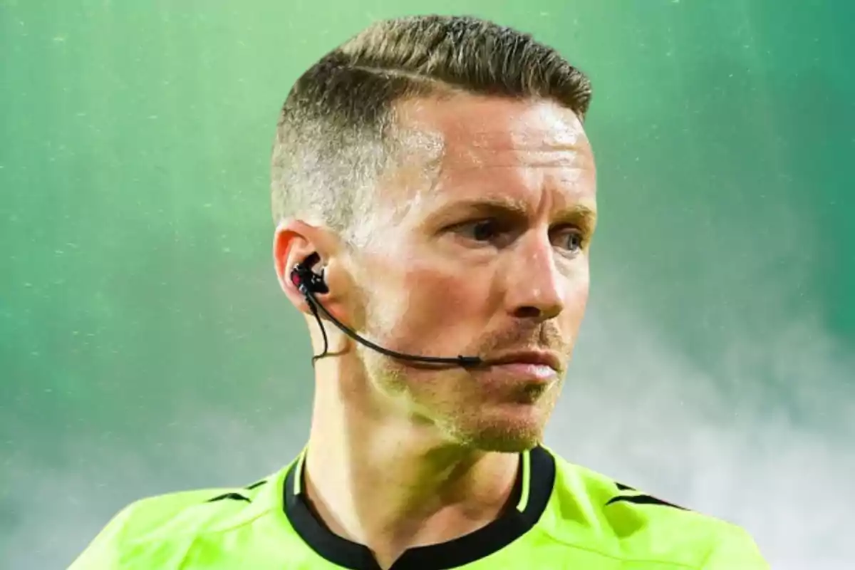 A soccer referee in a green uniform with an earpiece in a sports setting.