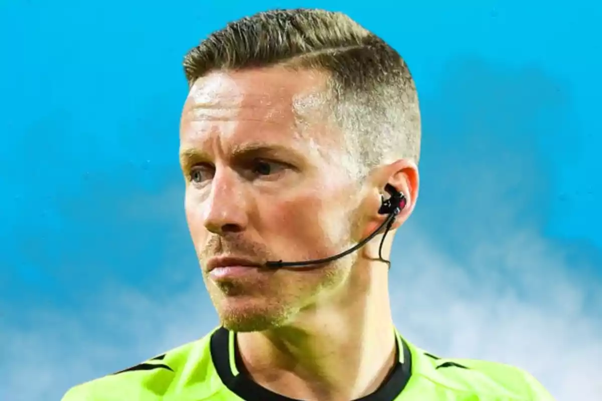 Un àrbitre de futbol amb uniforme verd i auricular en un estadi.