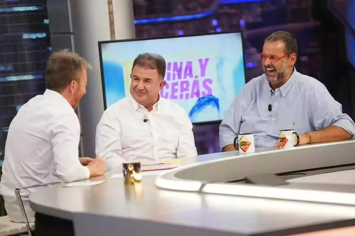 Martín Berasategui i David de Jorge amb Pablo Motos conversen i riuen a El Hormiguero amb una pantalla de fons que mostra text en colors brillants.