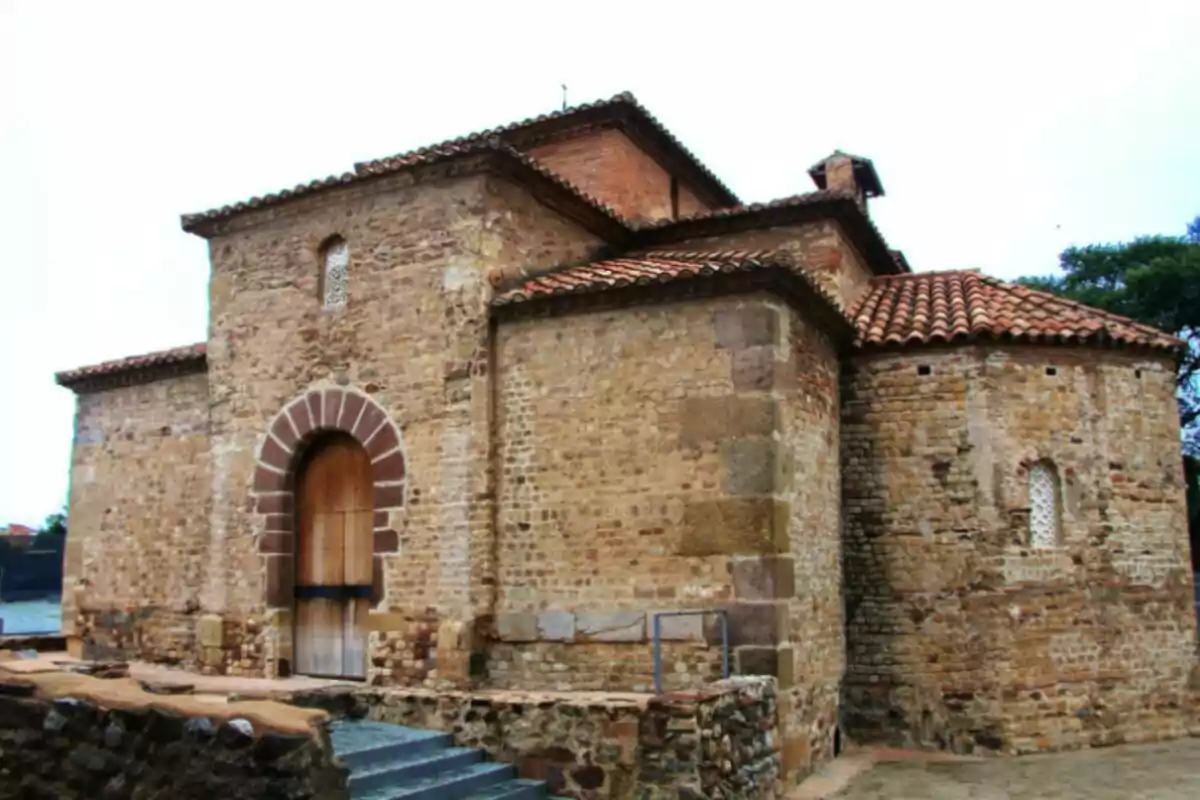 Una església antiga de pedra amb sostre de teules vermelles i una porta de fusta. Una església antiga de pedra amb sostre de teules vermelles i una porta de fusta.