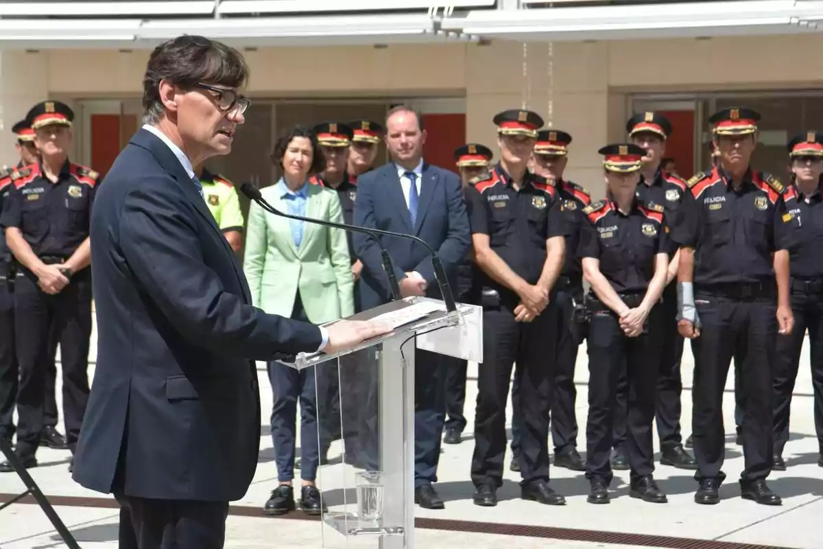 Salvador Illa en un podi parlant davant d'un grup de policies.