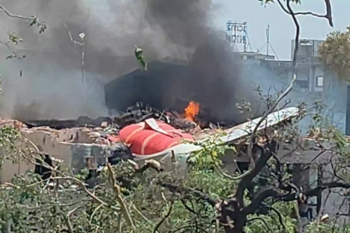 Avió accidentat sobre un edifici amb fum negre i foc sortint de les restes entre arbres i runa.