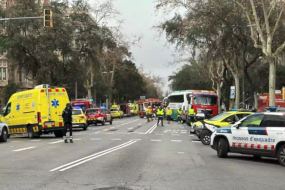 Un carrer amb vehicles d'emergència, incloent-hi ambulàncies i cotxes de policia, amb personal de seguretat i serveis d'emergència presents.