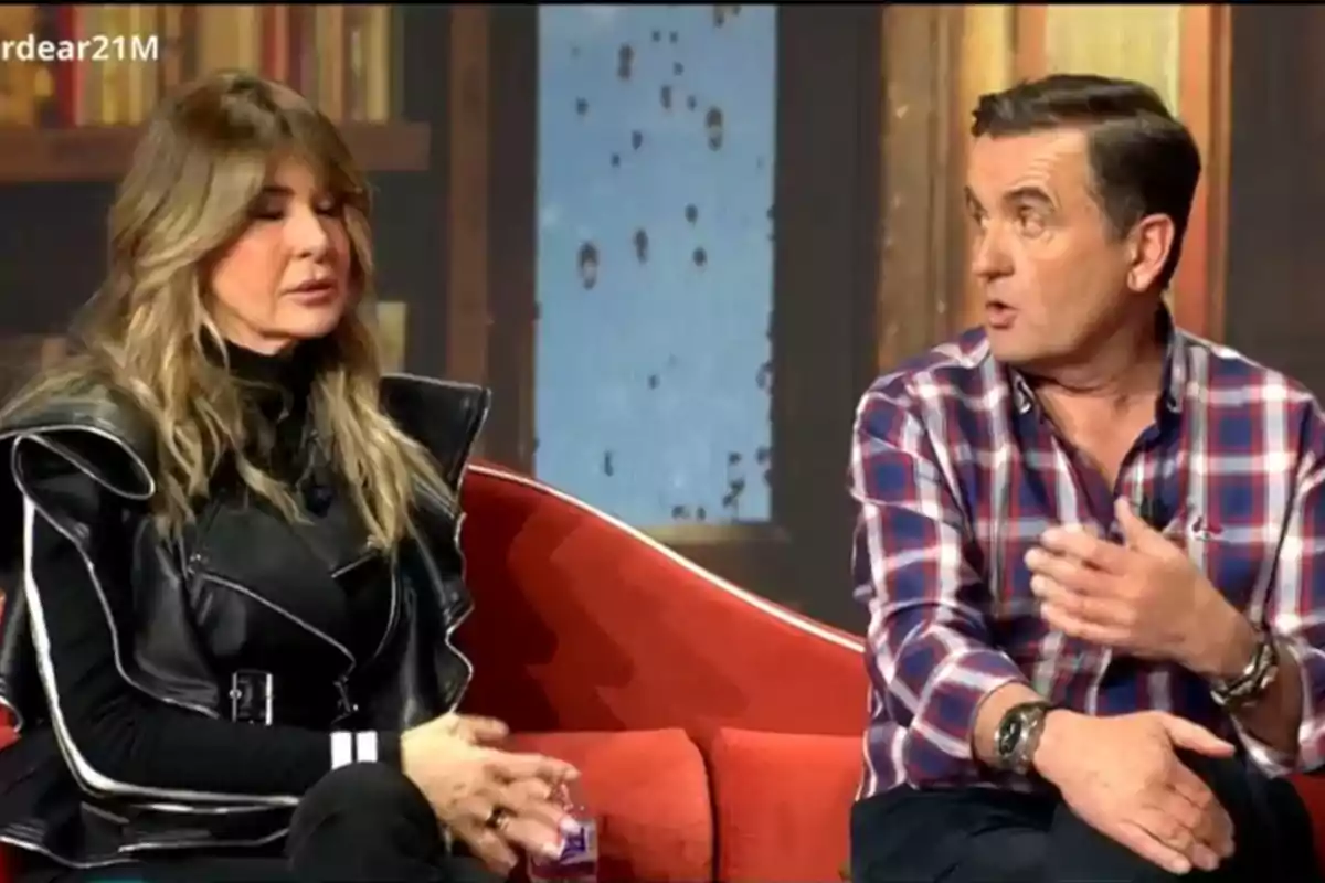 Dues persones assegudes en un sofà vermell conversant en un programa de televisió. Dues persones assegudes en un sofà vermell conversant en un programa de televisió.