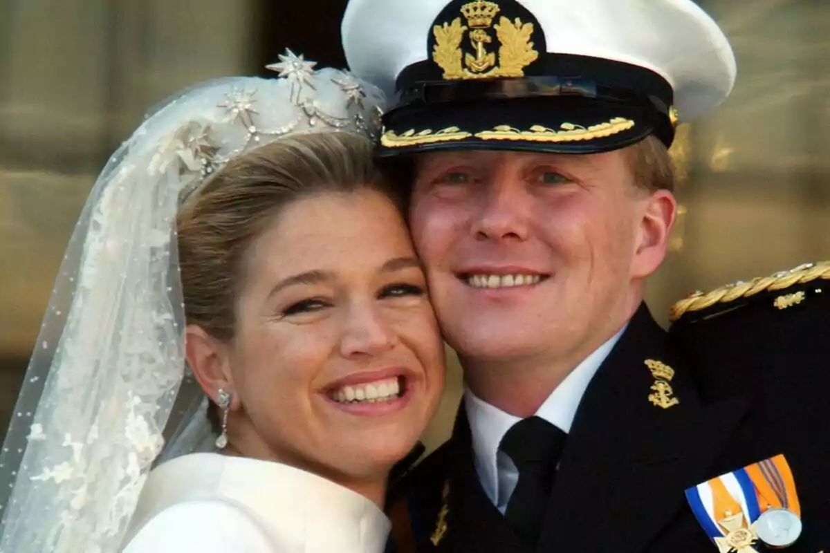 Una parella somrient al seu casament, amb la núvia portant un vel i el nuvi un uniforme naval. Una parella somrient al seu casament, amb la núvia portant un vel i el nuvi un uniforme naval.