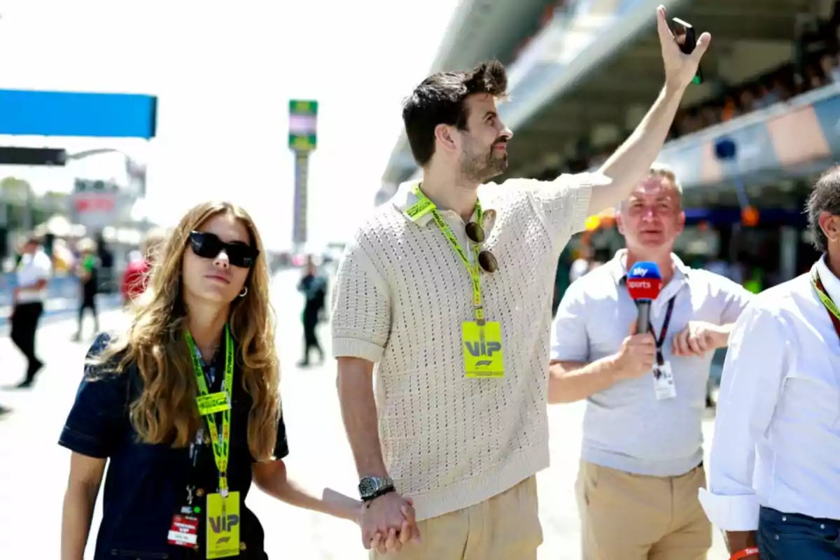 Una pareja camina de la mano en un evento deportivo, mientras un reportero sostiene un micrófono de Sky Sports en el fondo.