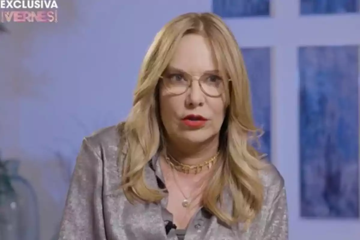Dona amb cabell ros i ulleres parlant en una entrevista amb fons blau. Dona amb cabell ros i ulleres parlant en una entrevista amb fons blau.