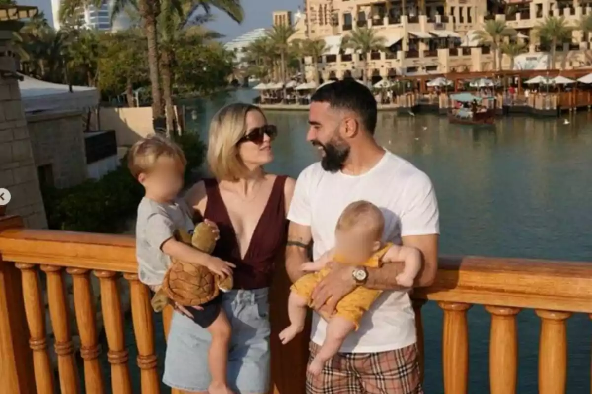 A smiling family posing on a wooden bridge with a landscape of palm trees and buildings in the background. A smiling family posing on a wooden bridge with a landscape of palm trees and buildings in the background.
