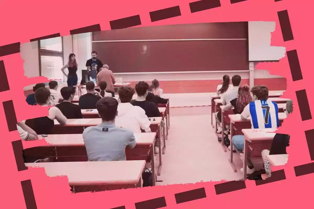 Un grup d’estudiants asseguts als pupitres dins d’una aula mentre observen tres persones dretes davant la pissarra.