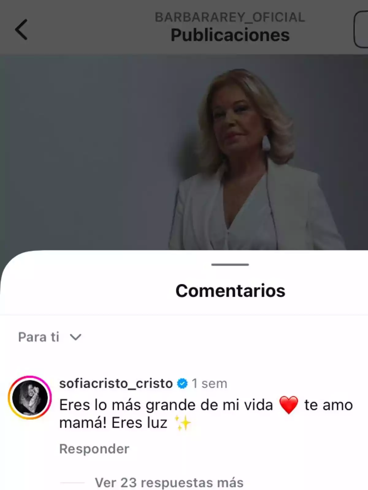 A blonde-haired woman poses in a white suit, while at the bottom of the image a social media comment expresses love and admiration for a mother.